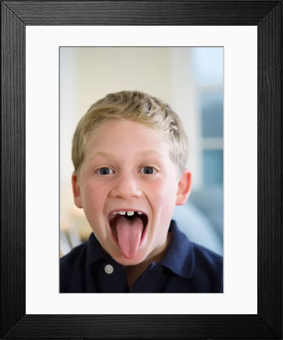 Framed Print : Portrait of a boy sticking out tongue