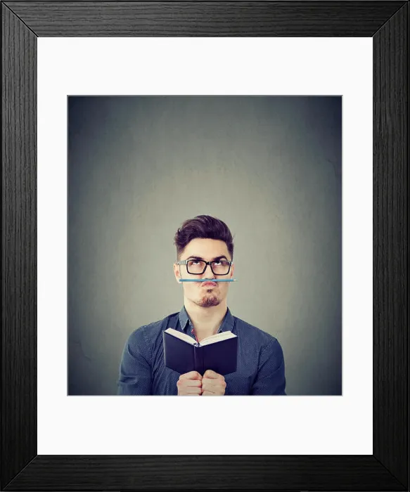 Framed Print : Young man with notepad playing with pencil instead of moustache fighting with boredom Framed Print : Young man with notepad playing with pencil instead of moustache fighting with boredom