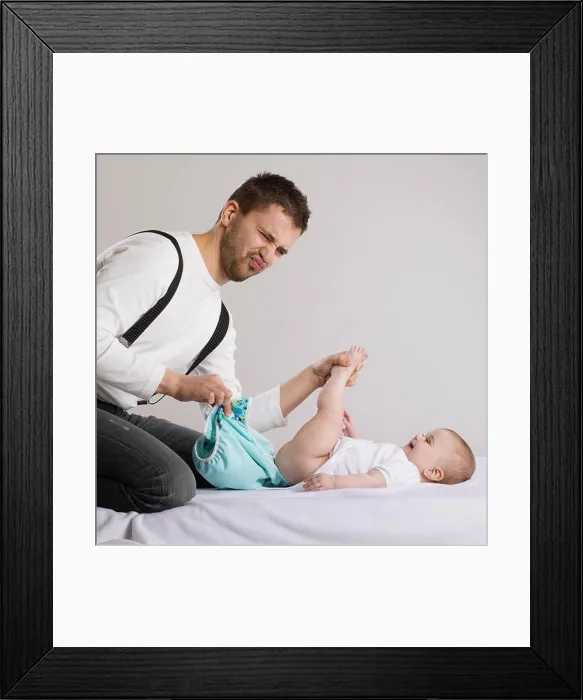 Framed Print : Young attractive father is changing nappy to his baby girl Framed Print : Young attractive father is changing nappy to his baby girl