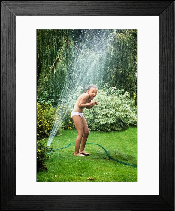 Framed Print : Young girl having fun while standing under garden fountain during hot summer day Framed Print : Young girl having fun while standing under garden fountain during hot summer day
