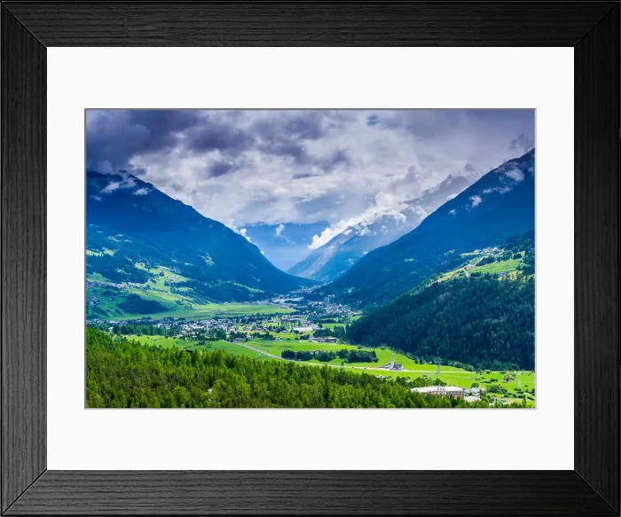 Framed Print : The town is located at the bottom of a narrow valley, surrounded by mountains and forest, dark clouds at the sky Framed Print : The town is located at the bottom of a narrow valley, surrounded by mountains and forest, dark clouds at the sky