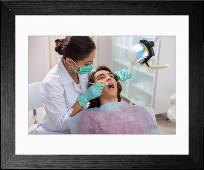 Framed Print : Concentrated woman dentist leaning over her male patient