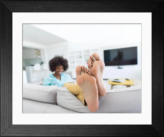 Framed Print : Young african american woman at home relaxing in her luxury lliving room reading a digital tablet surf internet Framed Print : Young african american woman at home relaxing in her luxury lliving room reading a digital tablet surf internet