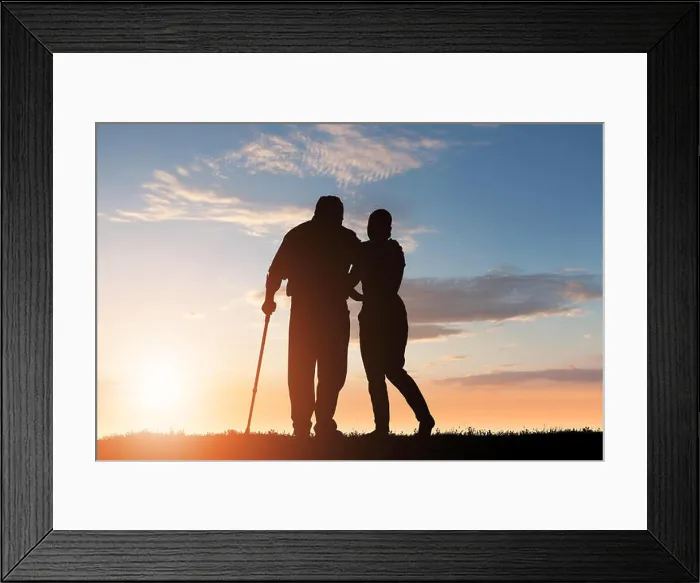 Framed Print : Silhouette Of Woman Assisting Her Disabled Father Walking In Park At Dusk Framed Print : Silhouette Of Woman Assisting Her Disabled Father Walking In Park At Dusk