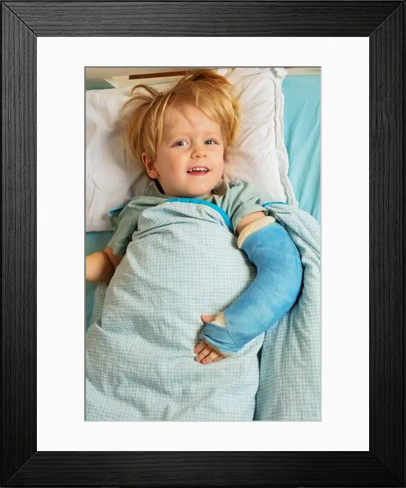 Framed Print : Blond boy in hospital bed with plaster cast on the broken hand Framed Print : Blond boy in hospital bed with plaster cast on the broken hand