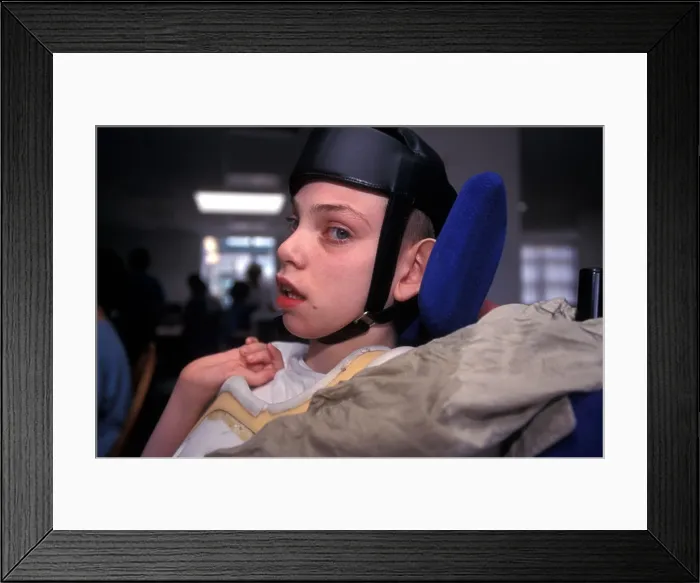 Framed Print : Young autistic boy in wheelchair wearing protective head gear at a special school London UK Framed Print : Young autistic boy in wheelchair wearing protective head gear at a special school London UK