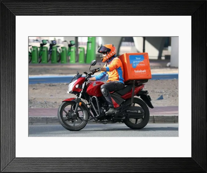 Framed Print : 22.03.2022, Dubai, , United Arab Emirates - Employee of food delivery service talabat riding a motorcycle in the city Framed Print : 22.03.2022, Dubai, , United Arab Emirates - Employee of food delivery service talabat riding a motorcycle in the city