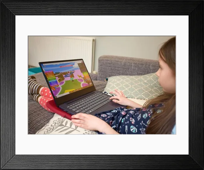 Framed Print : Young girl playing Roblox on laptop computer Framed Print : Young girl playing Roblox on laptop computer