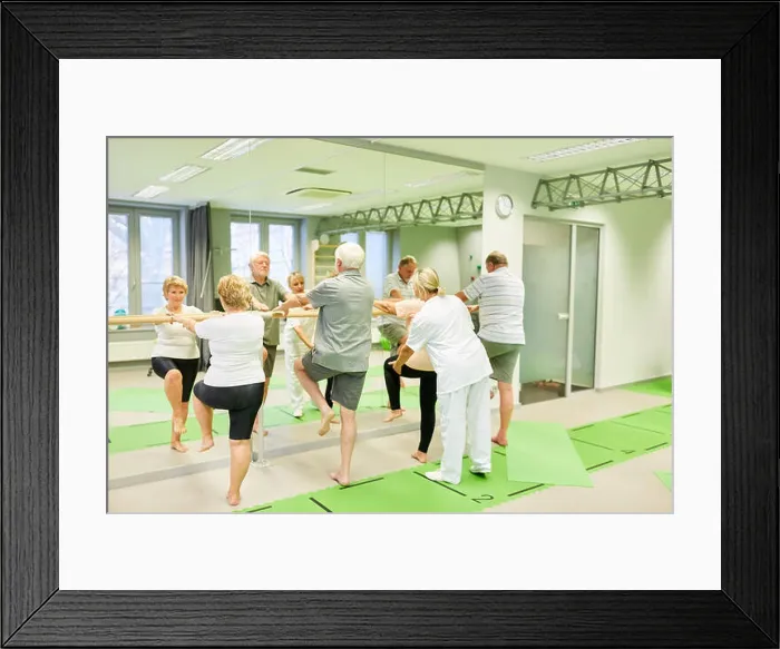 Framed Print : Therapist cares for seniors in physiotherapy on the ballet bar as a fall prevention Framed Print : Therapist cares for seniors in physiotherapy on the ballet bar as a fall prevention