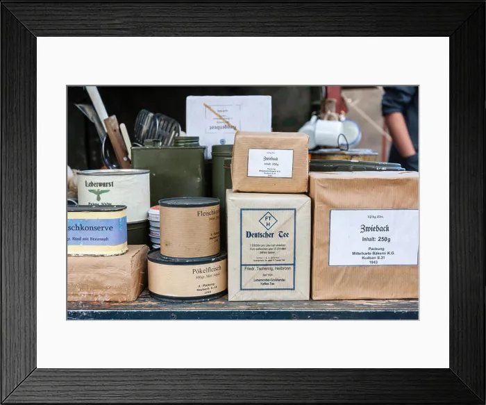 Framed Print : World war two re-enactment. Display of German food field supplies, packets and cans stacked with army labels on Framed Print : World war two re-enactment. Display of German food field supplies, packets and cans stacked with army labels on