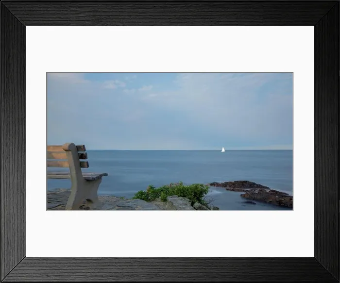 Framed Print : Lone empty bench, facing distant sailboat on smooth ocean Framed Print : Lone empty bench, facing distant sailboat on smooth ocean