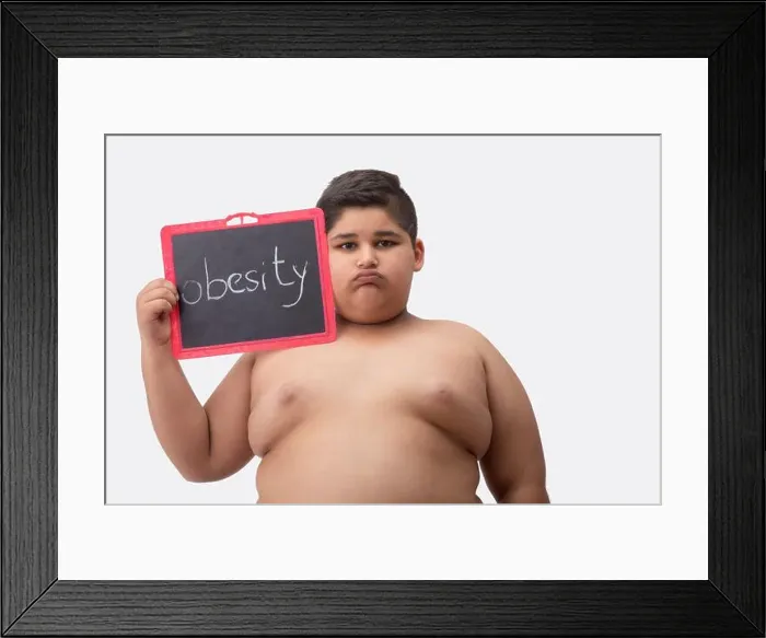 Framed Print : Young boy bare chested holding a small blackboard with obesity written on it Framed Print : Young boy bare chested holding a small blackboard with obesity written on it
