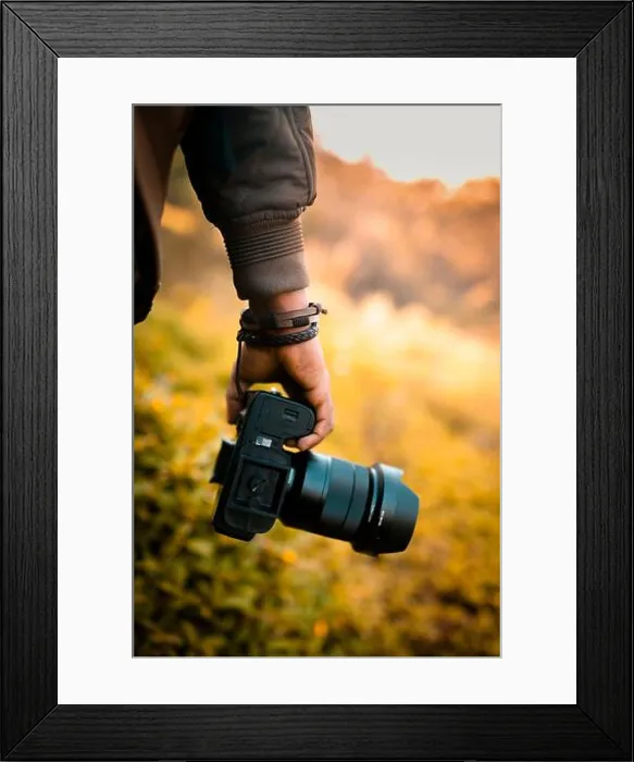 Framed Print : Photographer is holding a camera, DSLR camera with blur background selective focus image Framed Print : Photographer is holding a camera, DSLR camera with blur background selective focus image