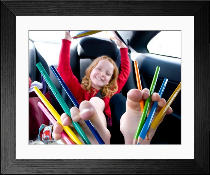 Framed Print : Red haired girl with multi-coloured pencils between her ten toes in the back of a car Framed Print : Red haired girl with multi-coloured pencils between her ten toes in the back of a car