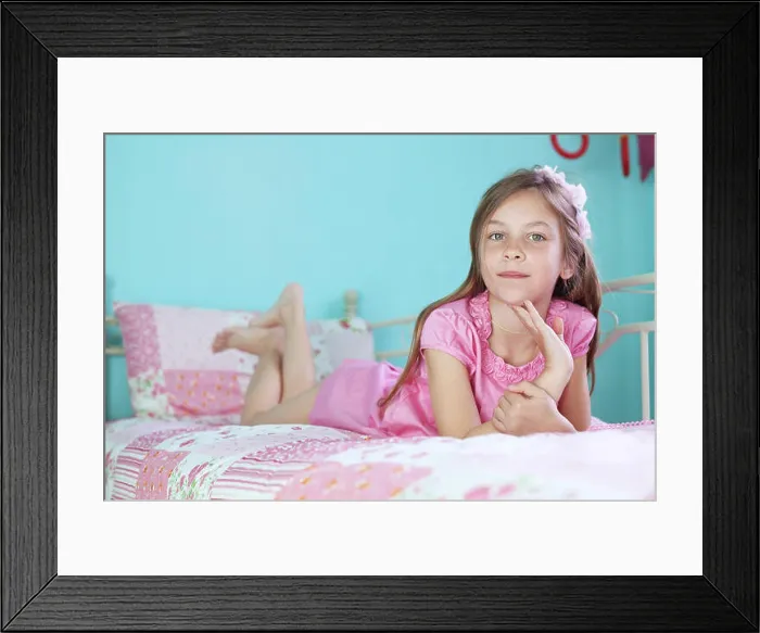 Framed Print : Portrait of 7 years old school girl resting on pink bed in her nursery at home Framed Print : Portrait of 7 years old school girl resting on pink bed in her nursery at home