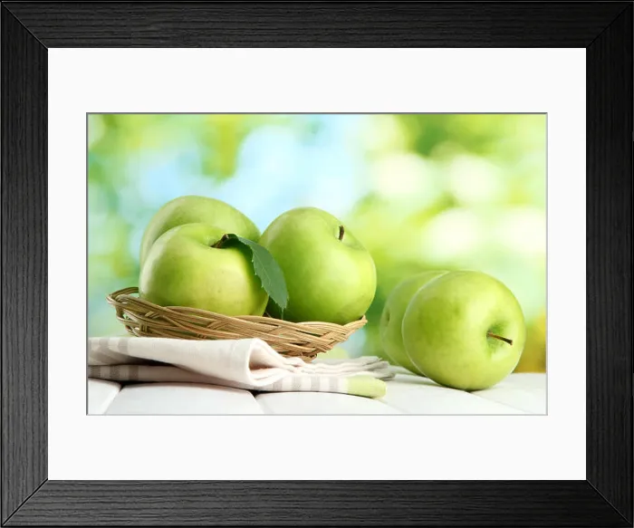 Framed Print : Ripe green apples with leaves in basket, on wooden table, on green background Framed Print : Ripe green apples with leaves in basket, on wooden table, on green background