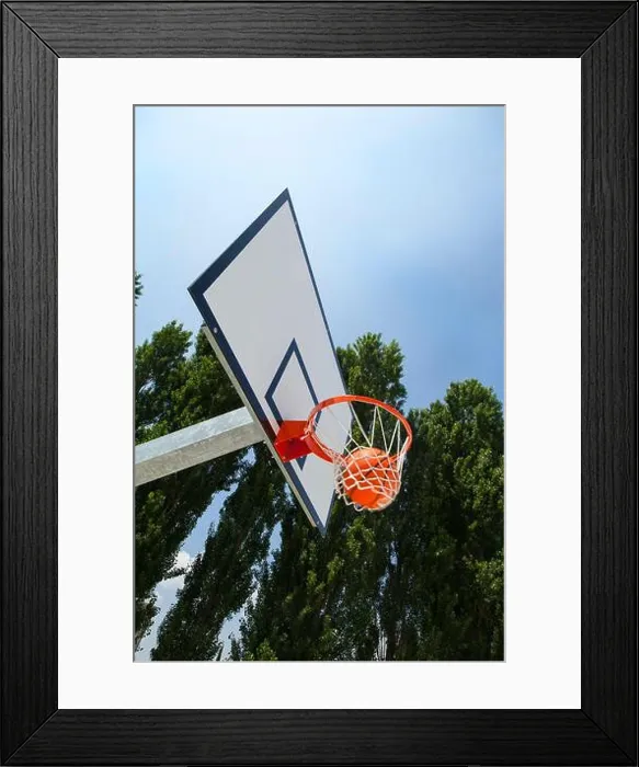 Framed Print : A basketball landing in the net of a backboard