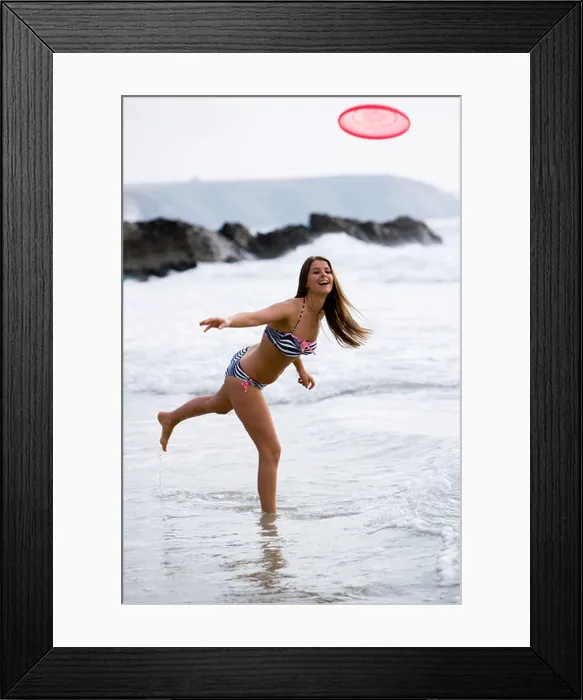 Framed Print : Woman in bikini throwing Frisbee at waters edge, Cornwall, UK Framed Print : Woman in bikini throwing Frisbee at waters edge, Cornwall, UK