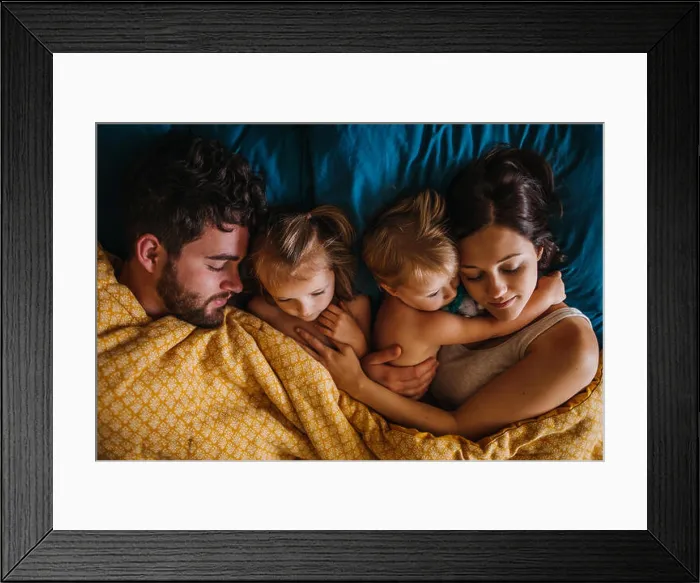 Framed Print : Family of four cuddling in bed with children