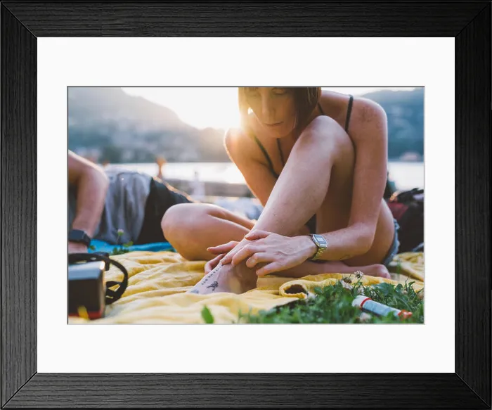 Framed Print : Young woman looking at foot tattoo on waterfront grass, Lake Como, Lombardy, Italy Framed Print : Young woman looking at foot tattoo on waterfront grass, Lake Como, Lombardy, Italy