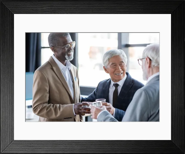 Framed Print : cheerful multiethnic business colleagues clinking glasses of whiskey in office Framed Print : cheerful multiethnic business colleagues clinking glasses of whiskey in office