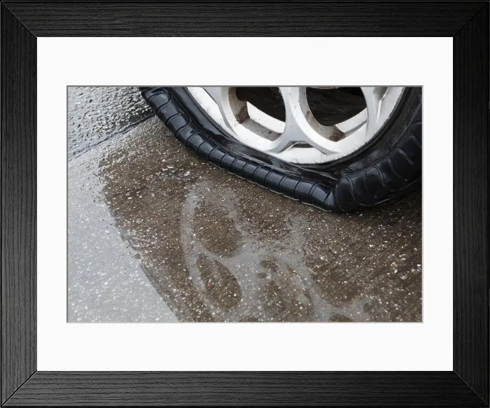 Framed Print : Flat tire on wet road