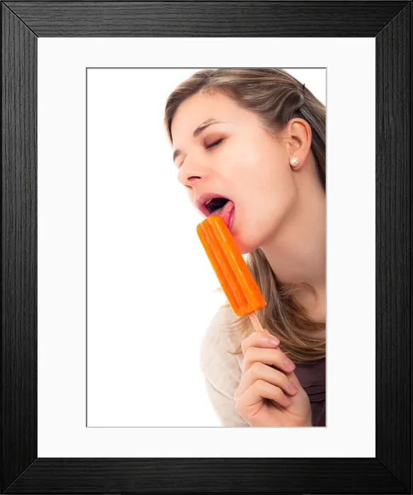 Framed Print : Young beautiful woman licking ice pop, isolated on white background Framed Print : Young beautiful woman licking ice pop, isolated on white background