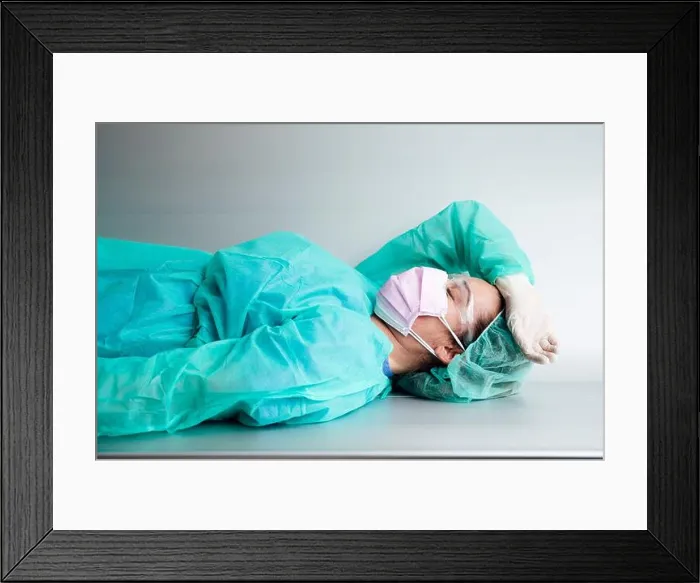 Framed Print : Tired female doctor wearing protective workwear resting on bench in hospital Framed Print : Tired female doctor wearing protective workwear resting on bench in hospital