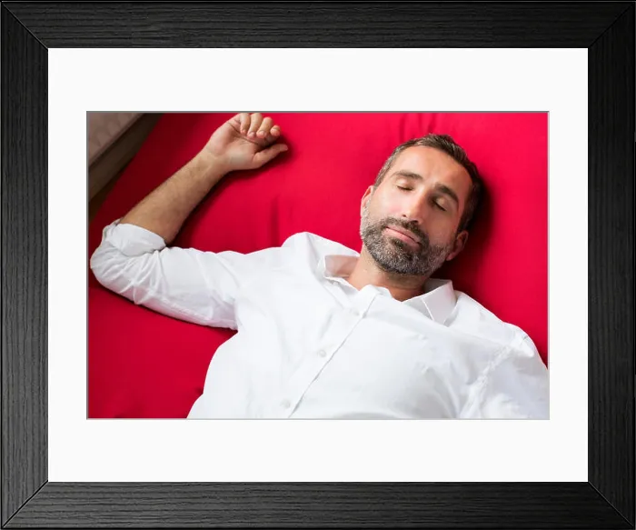 Framed Print : Portrait of a man in a white shirt lying on a red pillow and sleeping Framed Print : Portrait of a man in a white shirt lying on a red pillow and sleeping