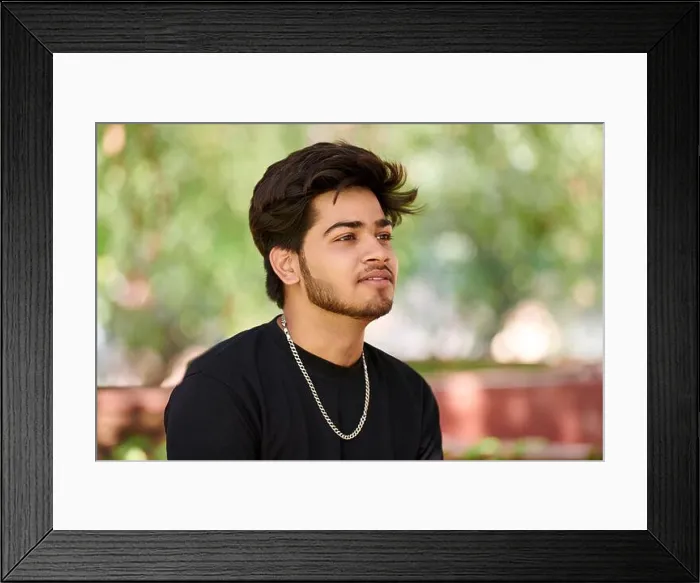 Framed Print : Attractive young indian man portrait in black t shirt and silver neck chain on outdoor green park background Framed Print : Attractive young indian man portrait in black t shirt and silver neck chain on outdoor green park background