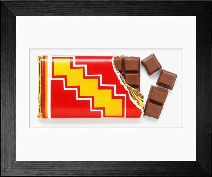 Framed Print : Bar of milk chocolate with one corner unwrapped and four squares broken off, close up