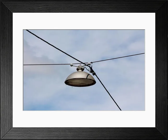 Framed Print : Side view of vintage retro old style large round street lamp within strong metal casing suspended with dark electrical Framed Print : Side view of vintage retro old style large round street lamp within strong metal casing suspended with dark electrical