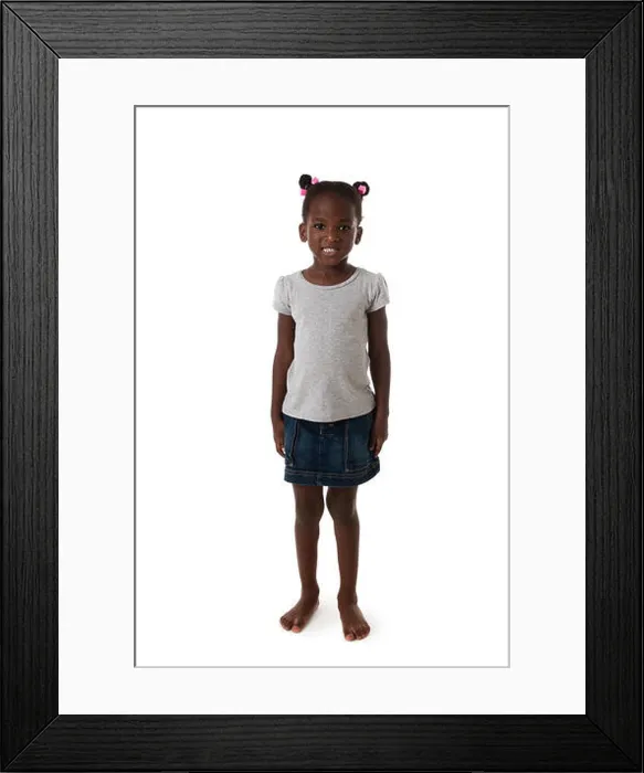Framed Print : Cute African little girl standing barefoot, looking to the camera on white background Framed Print : Cute African little girl standing barefoot, looking to the camera on white background