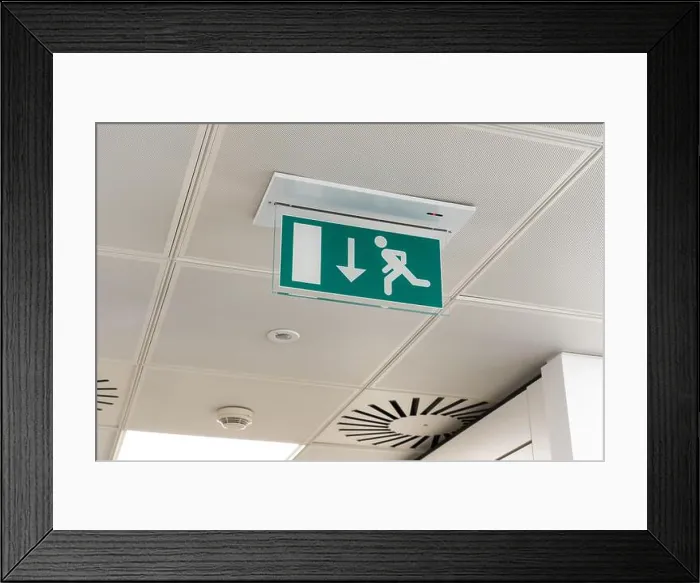 Framed Print : Ceiling mounted LED emergency fire exit sign with arrow pointing towards the fire door in a UK office Framed Print : Ceiling mounted LED emergency fire exit sign with arrow pointing towards the fire door in a UK office