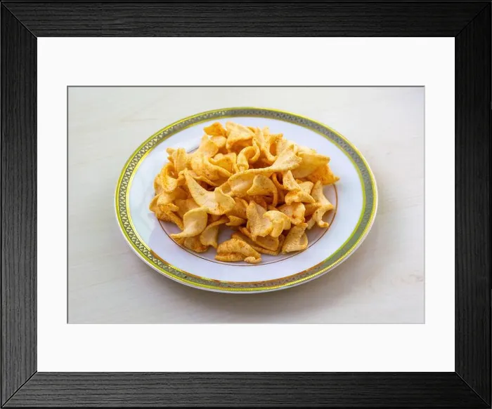 Framed Print : Crispy twist potato chips or aloo chips with tomato and paprika flavor, served on a white plate on a light wooden table