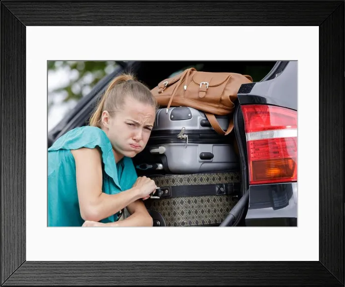 Framed Print : woman struggling to fix luggage in a car Framed Print : woman struggling to fix luggage in a car