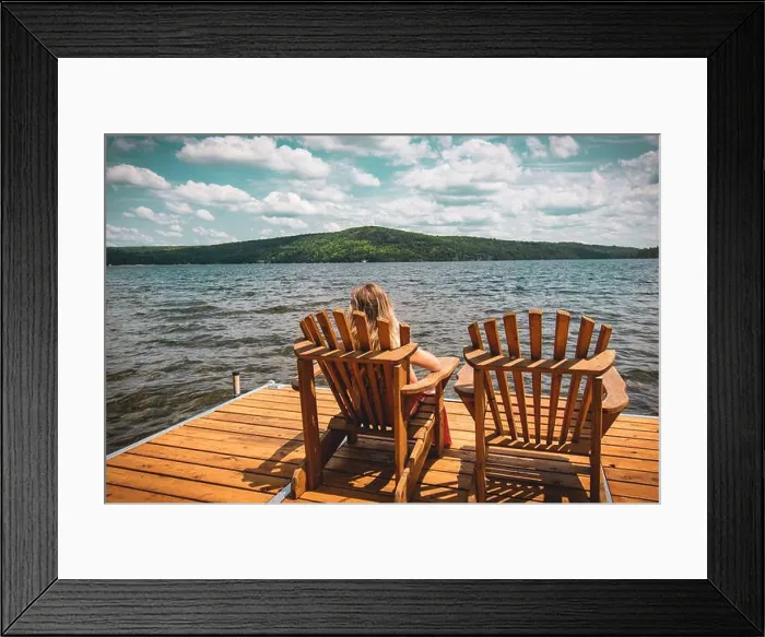 Framed Print : Person resting on a folding chair on a wooden dock on the sea under a cloudy sky and sunlight Framed Print : Person resting on a folding chair on a wooden dock on the sea under a cloudy sky and sunlight