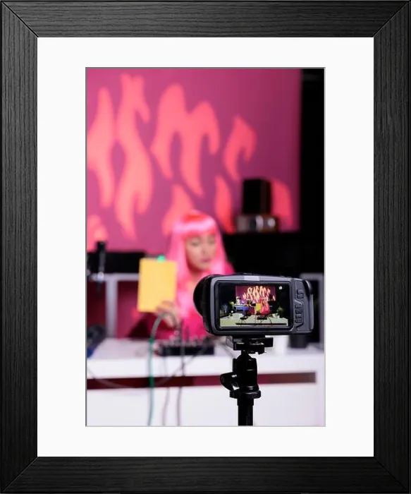 Framed Print : Influencer holding notebook showing product in front of camera while recording review using professional vlogging Framed Print : Influencer holding notebook showing product in front of camera while recording review using professional vlogging