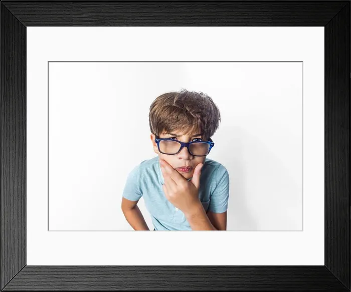 Framed Print : An exaggerated close up portrait of a funny little boy with glasses making a thinking face Framed Print : An exaggerated close up portrait of a funny little boy with glasses making a thinking face