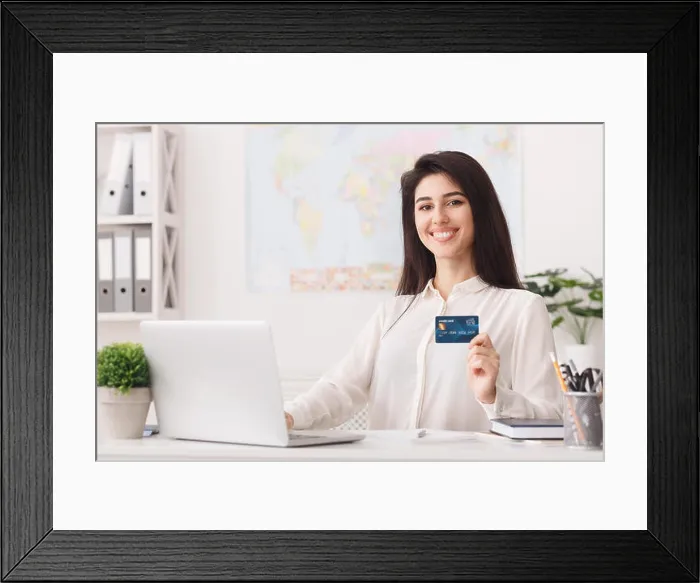 Framed Print : Travel agency. Woman showing credit card, looking at camera Framed Print : Travel agency. Woman showing credit card, looking at camera