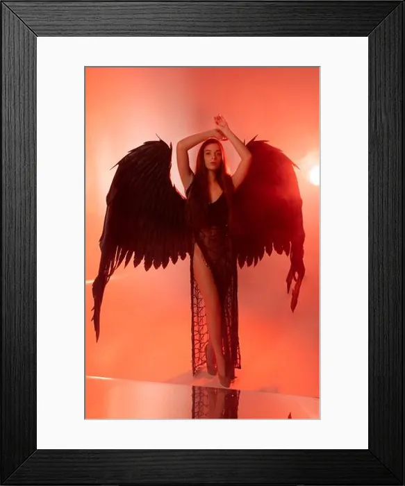 Framed Print : beautiful young model with big angel wings sitting in the studio. white background.black Angel Framed Print : beautiful young model with big angel wings sitting in the studio. white background.black Angel