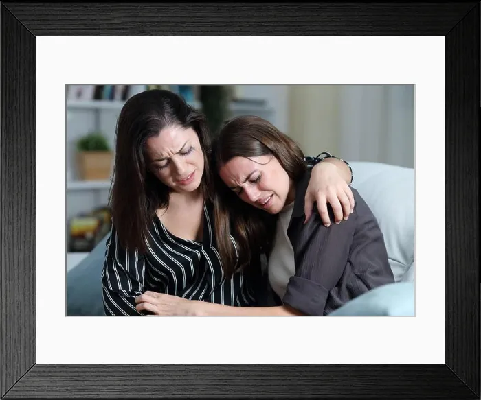 Framed Print : Two sad friends or sisters crying together on a couch in the living room at home Framed Print : Two sad friends or sisters crying together on a couch in the living room at home