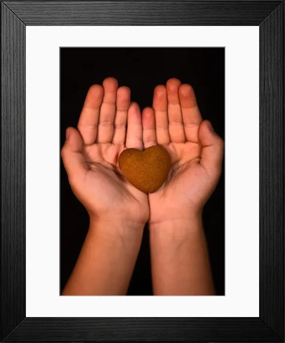 Framed Print : Vertical shot of a child's hands holding a heart-shaped cookie - human kindness concept Framed Print : Vertical shot of a child's hands holding a heart-shaped cookie - human kindness concept