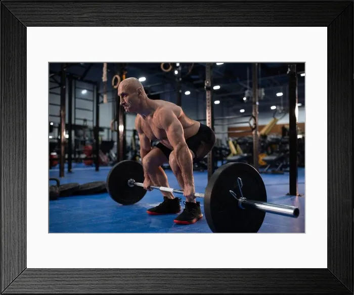 Framed Print : Full body powerful elderly man lifting barbell from floor while exercising during weightlifting training in gym