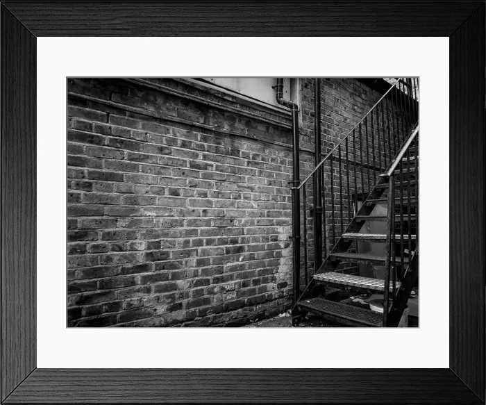 Framed Print : A old run down brick alleyway with a iron stairway in black and white Framed Print : A old run down brick alleyway with a iron stairway in black and white