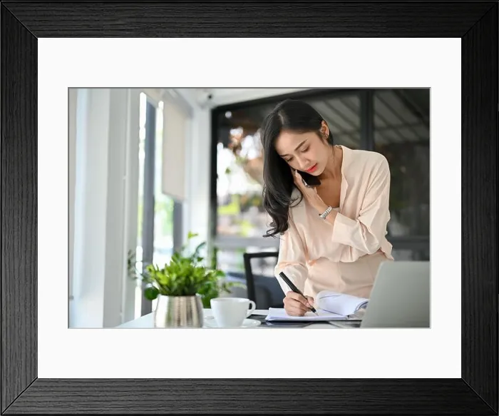 Framed Print : Busy and professional millennial Asian businesswoman is on the phone with a business partner Framed Print : Busy and professional millennial Asian businesswoman is on the phone with a business partner