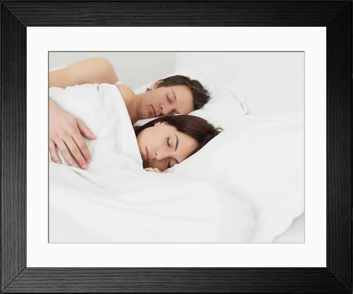 Framed Print : Young couple sleeping in bed man's arm around woman Framed Print : Young couple sleeping in bed man's arm around woman