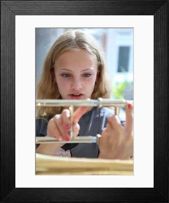 Framed Print : Girl holding trombone showing different slide positions Framed Print : Girl holding trombone showing different slide positions