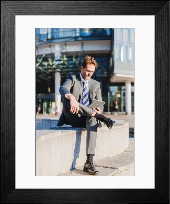 Framed Print : businessman makes a rest in the city and works with a tablet