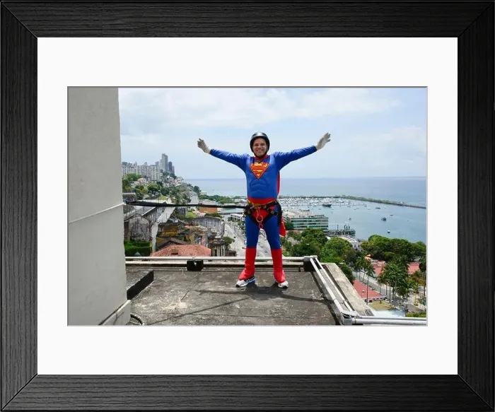 Framed Print : Man wearing black helmet and wearing a hero costume preparing to descend the Lacerda Elevator from Rappel